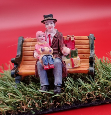 Miniatur Figur auf Bank mit Geschenken